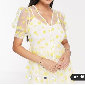 Sheer dress with yellow flowers and white trim.
